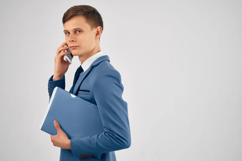 Деловой мужчина с синей папкой разговаривает по телефону