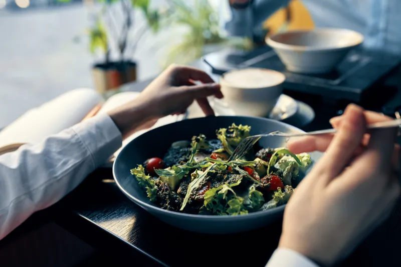 Свежий салат на тарелке, вкусная диетическая еда, вилка в руке, женские руки, кафе