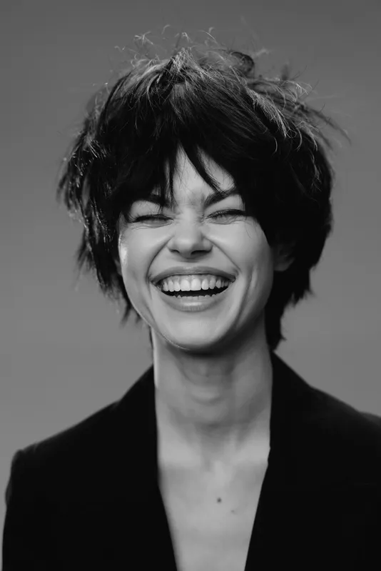 smiling woman with short hair wearing black blazer black and white portrait joyful positive emotion