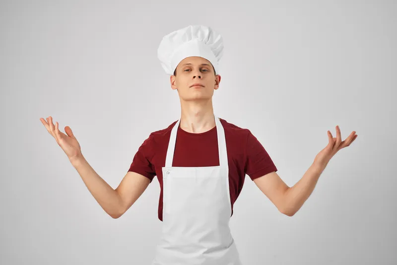 Мужчина в одежде повара жестикулирует рукой, демонстрируя профессиональную работу