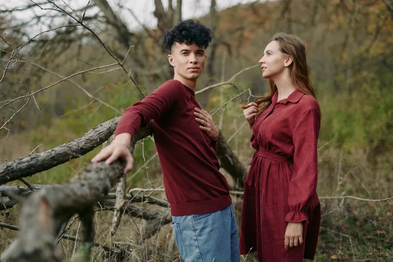 A candid scene features two young adults in a rustic outdoor setting, emphasizing authenticity and credibility through natural pose and sincere interaction.