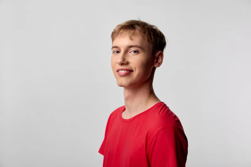 Smiling man in a red shirt in a studio, showcasing casual style, confidence, and approachable charm for lifestyle, fashion, and commercial use in advertising