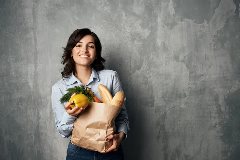 Весёлая брюнетка с сумкой продуктов