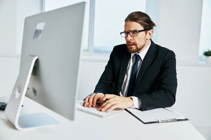 Офисный работник в костюме, работает в офисе с телефоном