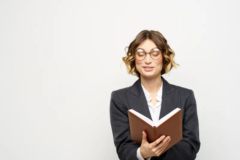 Женщина за работой с книгой в руке на светлом фоне