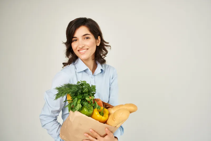 Жизнерадостная женщина с пакетом продуктов в супермаркете, шопинг, образ жизни