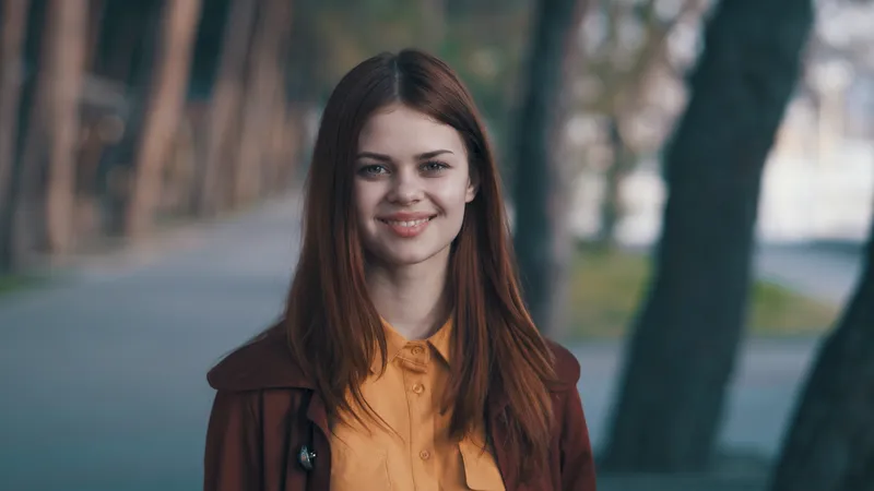 Весёлая симпатичная женщина в пальто улыбается на улице в парке