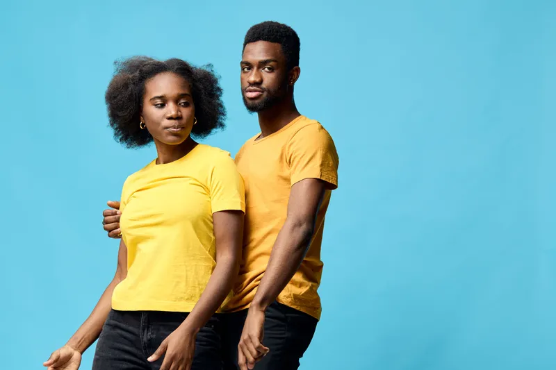 Young African couple in matching yellow outfits on a blue background, showcasing love and confidence in a vibrant, uplifting atmosphere