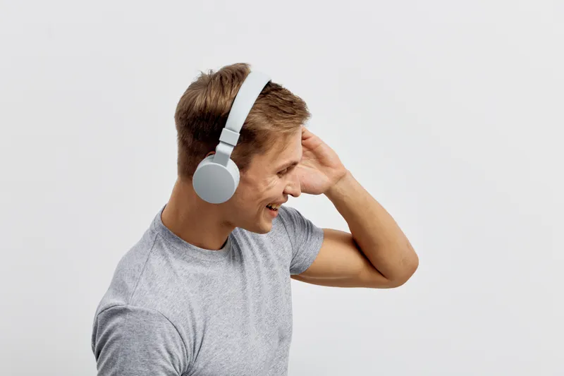smiling young caucasian man wear grey t-shirt use wireless headphones listen music isolated on white background digital detox mental health concept