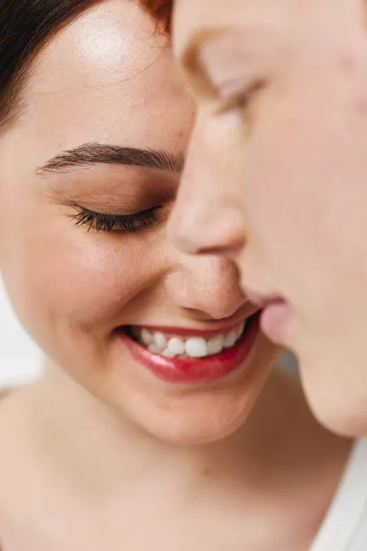 Closeup of smiling woman and man touching heads with eyes closed, showing happiness and affection in intimate moment of love and connection.