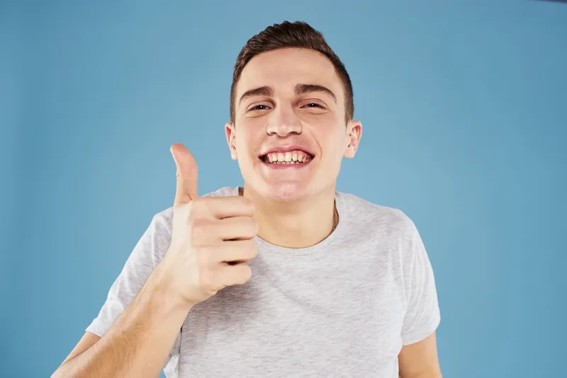 Эмоциональный мужчина в белой футболке, кадрированный вид на синем фоне