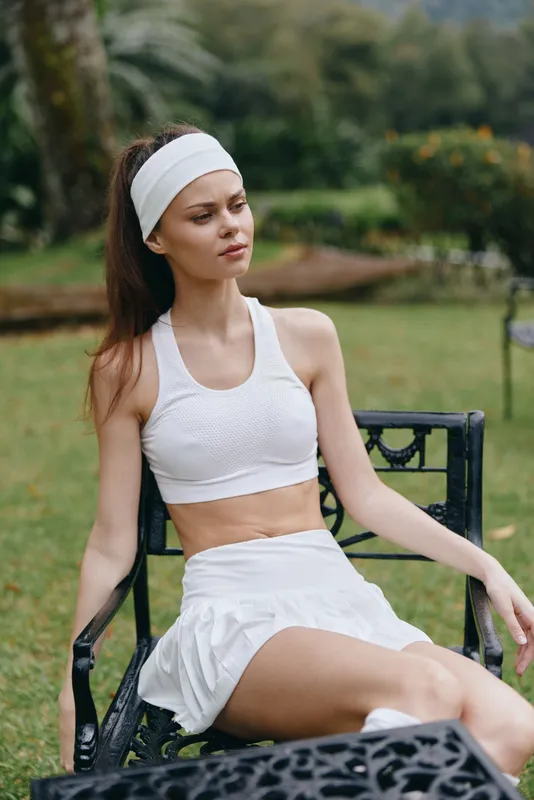 Young woman in sportswear relaxing outdoors on a sunny day, showcasing healthy lifestyle and fitness, in a green park setting