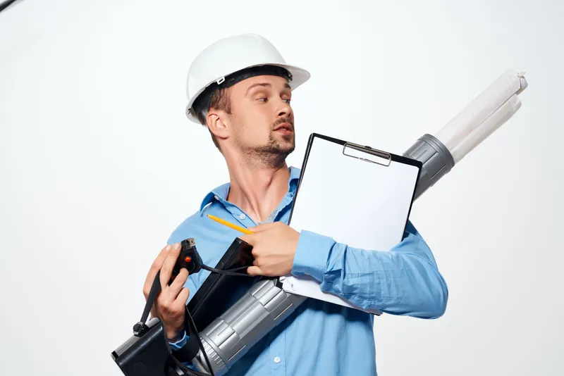 Инженер в белой каске с чертежами и документами, профессионал за работой