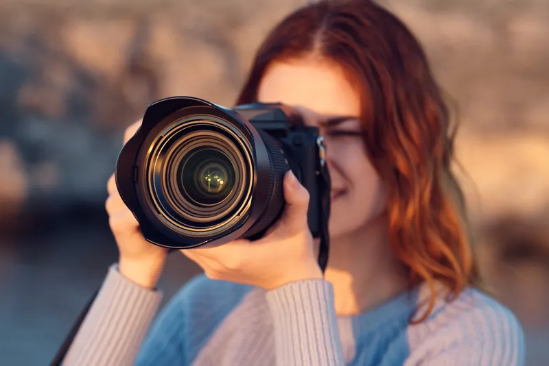 Женщина с профессиональным фотоаппаратом на открытом воздухе в горах, вид спереди
