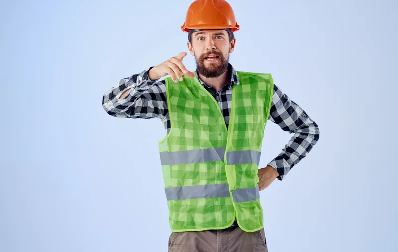 Фрагмент изображения инженера-строителя в светоотражающем жилете с косой на синем фоне