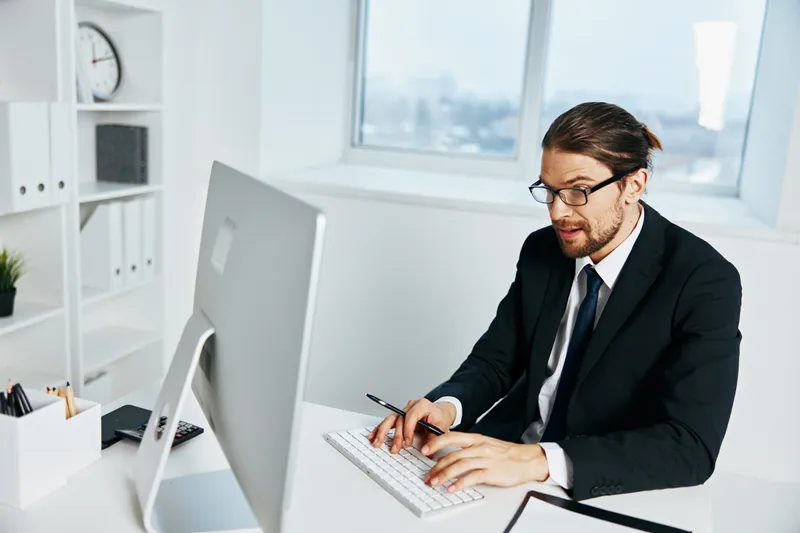 Офисный работник в костюме работает в офисе с телефоном