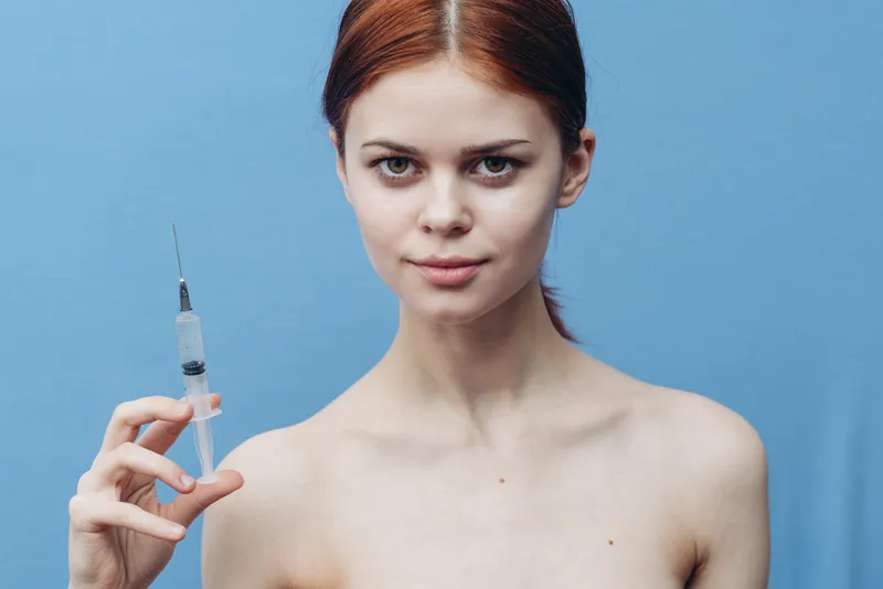 Женщина со шприцем, обнаженные плечи, омолаживающая инъекция