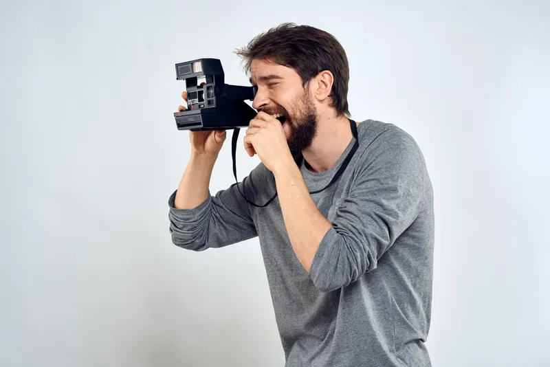 Фотограф-мужчина с профессиональной камерой, работа в студии, технологии, современное искусство, светлый фон