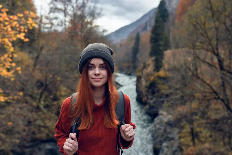 Женщина-туристка путешествует по горам и рекам, наслаждаясь свежим воздухом и природой