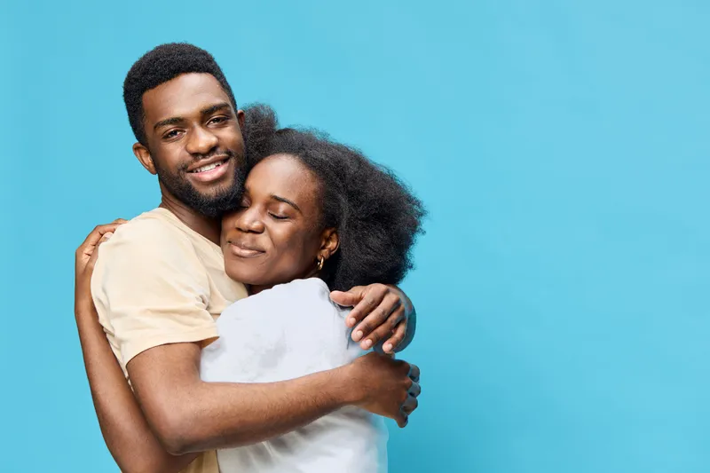 Young couple embracing with joy against a vibrant blue background, exuding warmth and love, perfect for relationship themes and emotional expressions