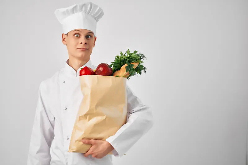 Мужчина в форме шеф-повара с упаковкой продуктов для работы в ресторане, сервис доставки