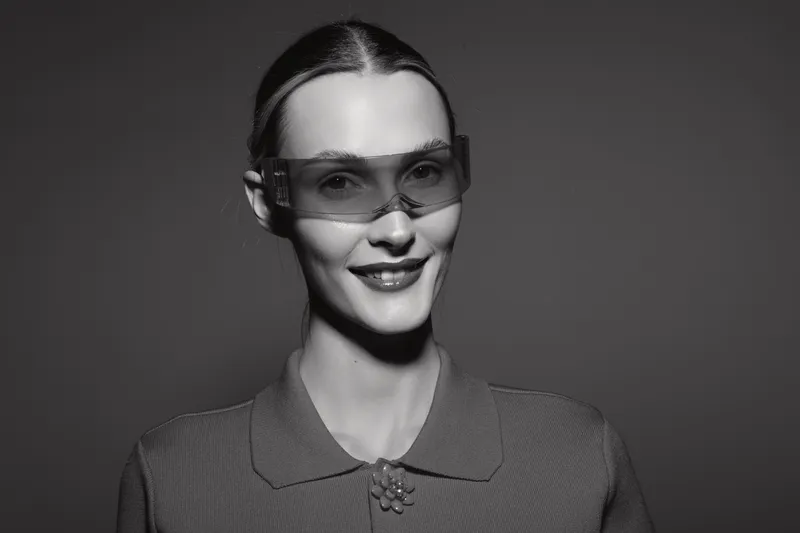 Young white woman with pale skin wearing futuristic glasses smiles in studio. Concept of modern technology and fashion style.