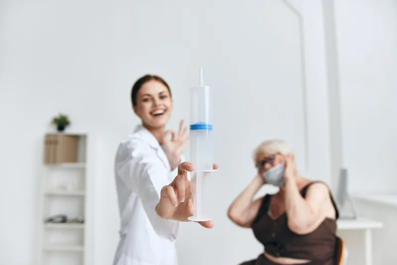 Медсестра делает инъекцию пожилой женщине, вакцинация в больнице