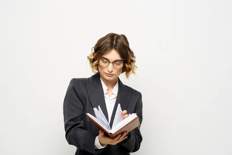 Женщина за работой с книгой в руке на светлом фоне