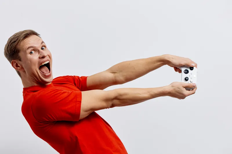Excited man in bright red t-shirt taking a selfie with a smartphone, expressing joy and enthusiasm, isolated on plain white background, studio shot, lifestyle concept, cheerful emotions, casual style