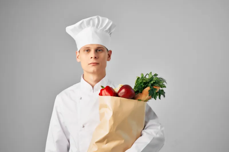 Мужчина в форме шеф-повара с упаковкой продуктов для доставки ресторанного сервиса