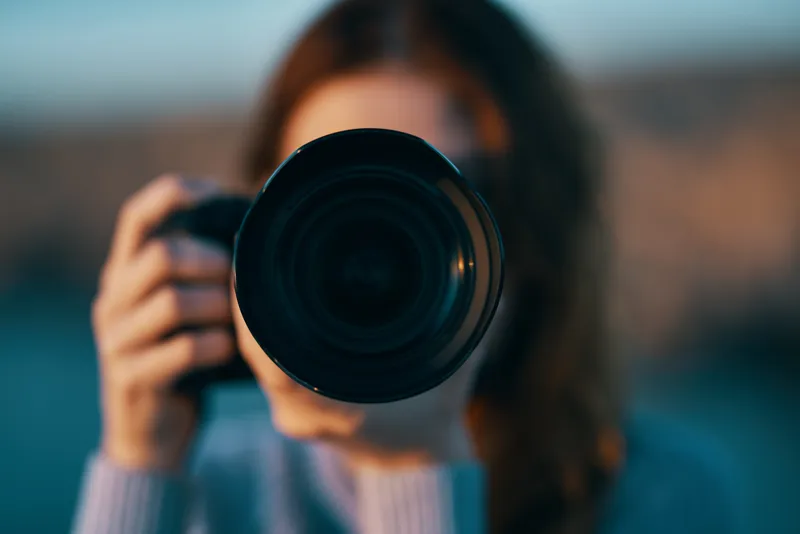Портрет женщины-фотографа с профессиональной камерой на открытом воздухе в горах