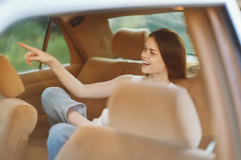 Cheerful young woman enjoying a scenic ride in a car, exuding happiness and relaxation, with a warm color palette and soft background blur, perfect for travel concepts.