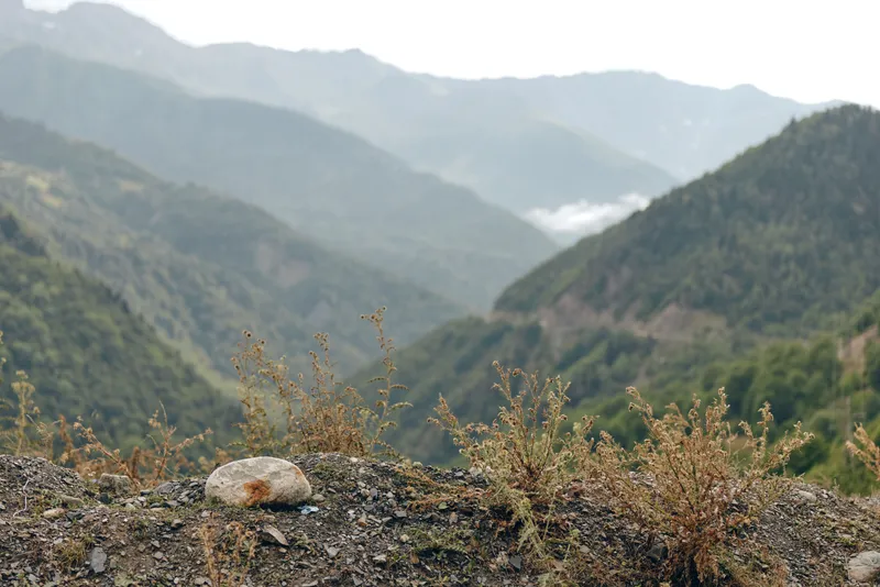 Mountain valley landscape with rocky foreground and dry plants, misty layers of hills in distance, natural scenery for travel outdoor serenity