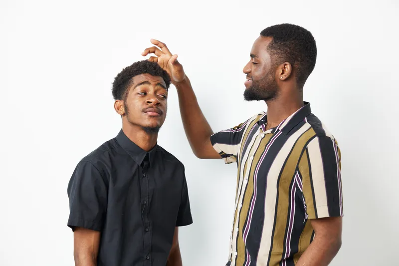Two black men chatting and having fun together, showcasing a playful moment. Their expressions reflect joy and friendship, creating a warm and inviting atmosphere.