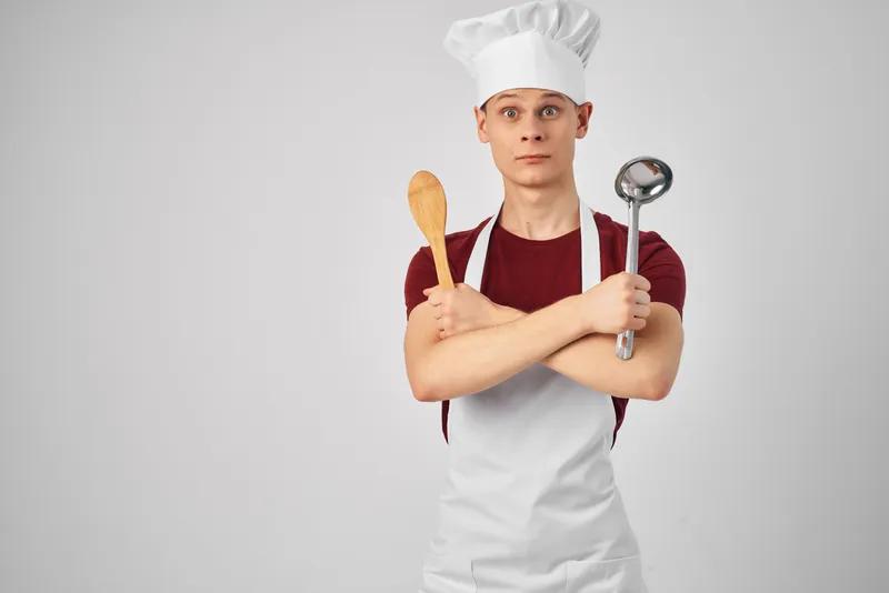 Мужчина в белом фартуке, кухонная утварь, работа по приготовлению пищи