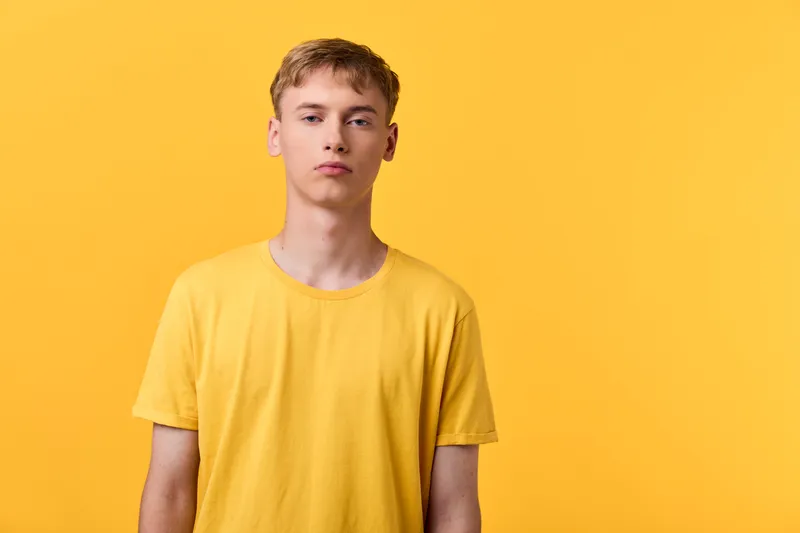 Man wearing a yellow tshirt stands against a solid yellow background in a clean studio setting, showcasing vibrant color harmony, minimalist composition, bold fashion focus, and a calm confident