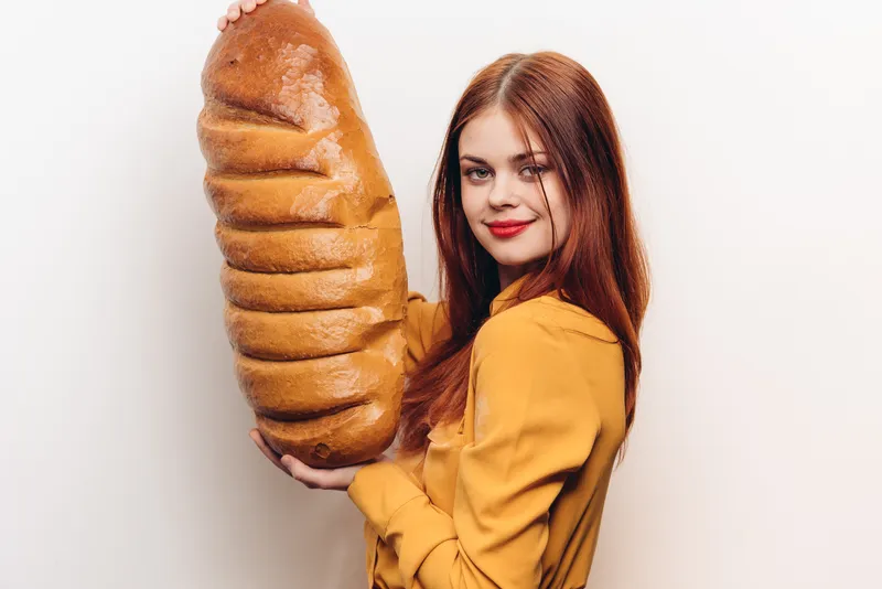 Эмоциональная женщина с большим бутоном на светлом фоне, в жёлтой рубашке и с ярким макияжем