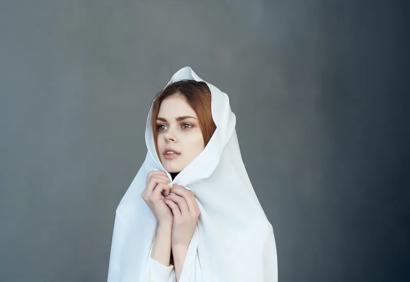 Красивая женщина накрывается белой тканью, на голове макияж, модная фотостудия