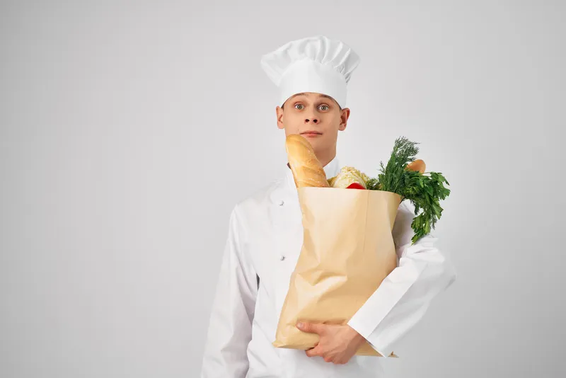 Эмоциональный мужчина-шеф-повар с пакетом продуктов