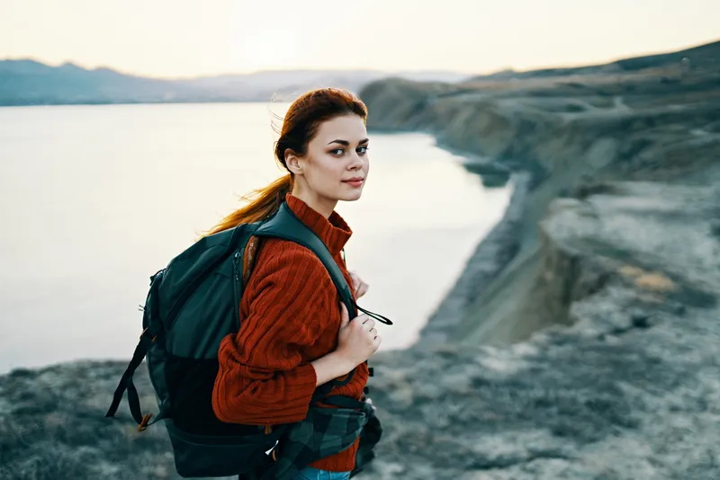Женщина на отдыхе в горах на фоне заката и моря