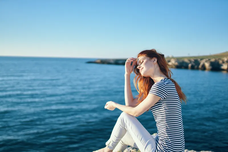 Женщина на скале у моря в горах, закат, лето