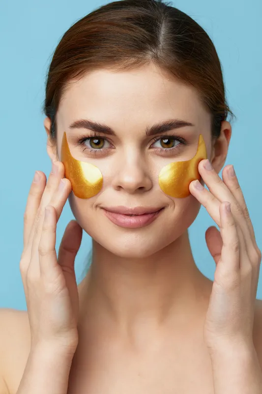Женщина наносит омолаживающий уход за кожей, веселясь после душа, на синем фоне