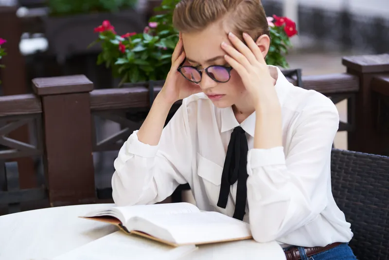 Студент с книгой в руках отдыхает на улице, весело прогуливаясь по городу и общаясь