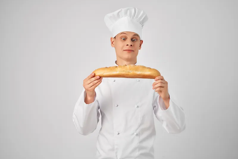 Повар-мужчина держит в руках багет, свежий продукт, профессиональная работа