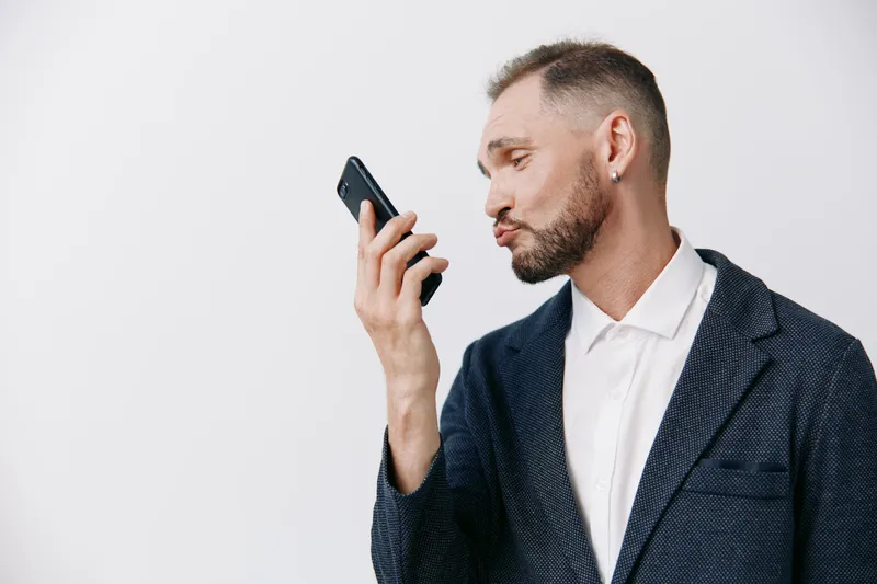 A professional businessman studies a smartphone with focused calm emotion on an isolated colored background, conveying confidence, technology usage, and modern work style.