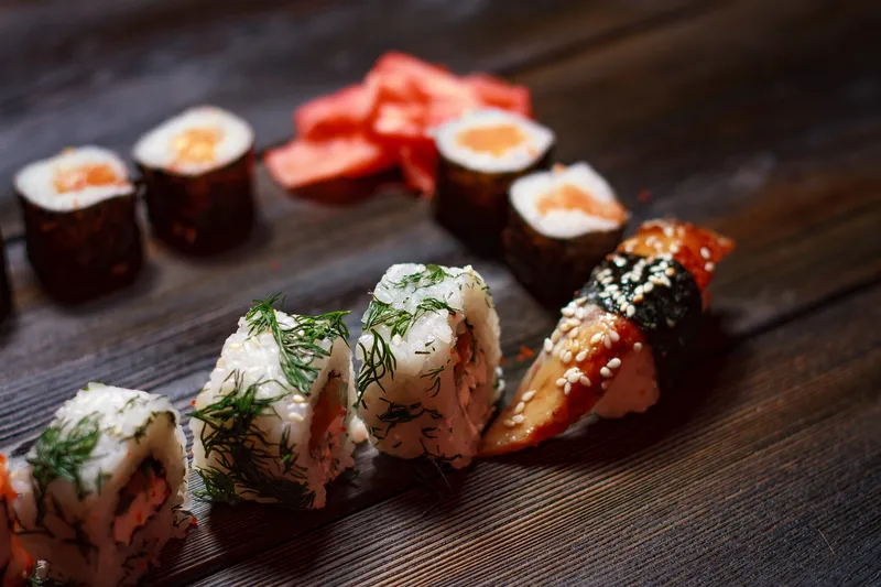 Роллы суши, палочки для еды, японская кухня, доставка еды на деревянном столе