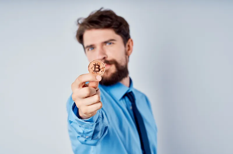 Мужчина с золотой монетой биткоина в офисе