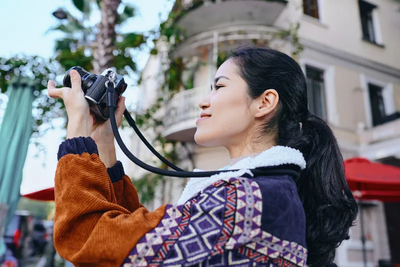 Woman with camera on city street, outdoor photography, stylish jacket, urban backdrop, candid mood, travel vibe, street photography, lens in focus, creative expression, daily life story