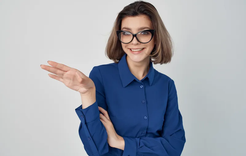 Женщина в синей рубашке и очках, выражающая эмоции менеджера