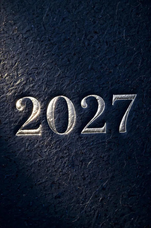 Серебристые цифры 2027 на тёмной фактурной поверхности